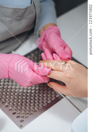 A manicure specialist applies moisturizing oil to nails and fingers, providing care and hydration for healthy, smooth hands A manicure specialist applies moisturizing oil to nails and fingers, providing care and hydration for healthy, smooth hands 123973802