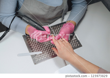 A nail technician performs a hardware manicure on a client, removing gel polish and providing thorough nail care for a polished look 123973829