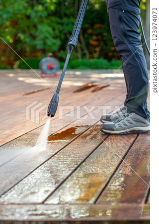 cleaning terrace with a power washer - high water pressure cleaner on wooden terrace surface 123974071