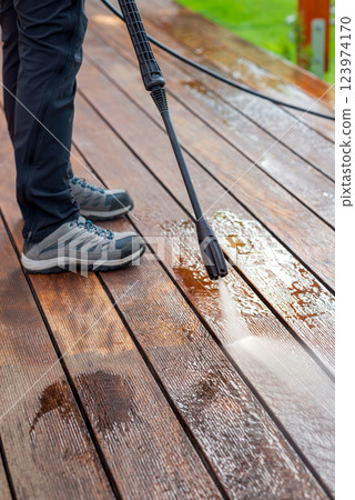 cleaning terrace with a power washer - high water pressure cleaner on wooden terrace surface 123974170