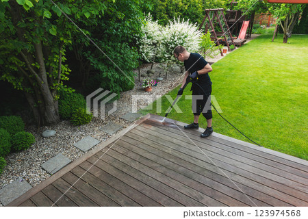 man cleaning terrace with a power washer - high water pressure cleaner on wooden terrace surface 123974568