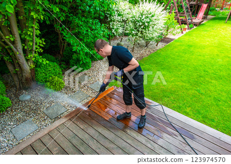 man cleaning terrace with a power washer - high water pressure cleaner on wooden terrace surface man cleaning terrace with a power washer - high water pressure cleaner on wooden terrace surface 123974570