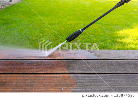 cleaning terrace with a power washer - high water pressure cleaner on wooden terrace surface cleaning terrace with a power washer - high water pressure cleaner on wooden terrace surface 123974583
