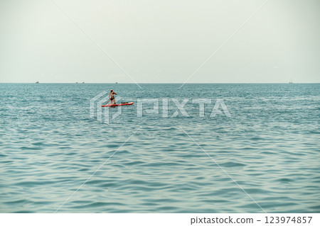Paddleboarder Enjoying Calm Waters on a Peaceful Afternoon Paddleboarder Enjoying Calm Waters on a Peaceful Afternoon 123974857