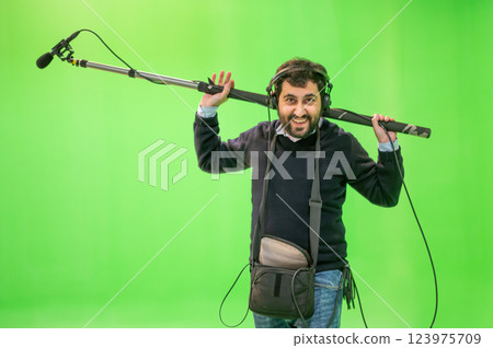 Boom microphone operator testing sound at TV studio on green key chroma background. 123975709