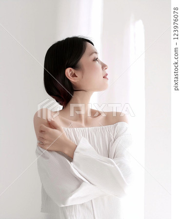 一名婦女站在窗邊。垂直影像。白色背景和白色窗簾。 123976078