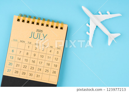 July 2025 calendar and airplane toy on blue background. 123977213