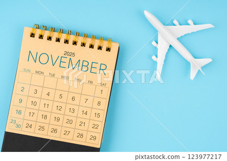 November 2025 calendar and airplane toy on blue background. November 2025 calendar and airplane toy on blue background. 123977217