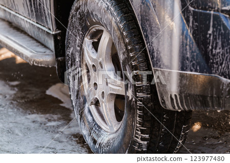 Close-up Image of a Car Wheel Covered with Soap Foam During a Vehicle Wash 123977480