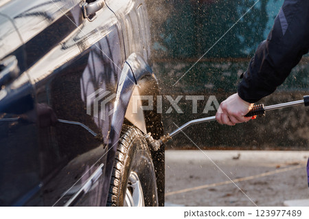 Close-Up of a Person Pressure Washing a Car Tire and Fender Outdoors Close-Up of a Person Pressure Washing a Car Tire and Fender Outdoors 123977489
