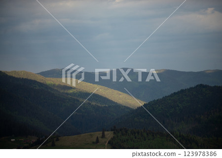 Mountains bathed in soft sunlight during twilight hours showcasing the beauty of nature in a serene landscape 123978386