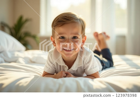 Happy young boy lying on a bed while smiling in a bright room during daylight 123978398