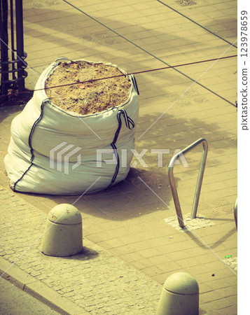 Bag of sand on sidewalk. 123978659