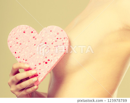 Naked woman holding pink heart sponge in hands. 123978789