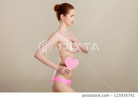 Naked woman holding pink heart sponge in hands. 123978791