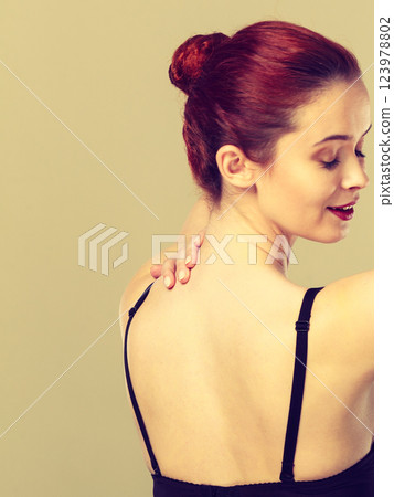 Woman dressing up her bra rear view 123978802