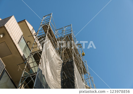 [Large-scale apartment building repair work: scaffolding and cranes] 123978856