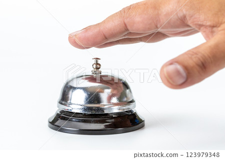 Close-up of a shiny silver service bell and a hand reaching out to ring it. Close-up of a shiny silver service bell and a hand reaching out to ring it. 123979348