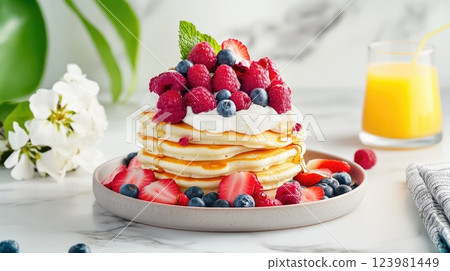 Delicious stack of fluffy pancakes topped with fresh berries and cream on a marble countertop 123981449