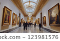 People walking inside art gallery exploring famous artworks, visitors appreciating gallery masterpieces exhibited beautifully, bright spacious gallery interior demonstrating refined ambiance. 123981576