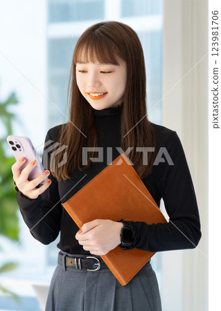 微笑的女商人拿著智慧型手機和活頁夾 123981706