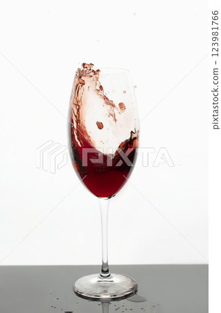 Red wine in glass. Splashes of red wine. Transparent glass with wine or juice on white background. Isolated object. Red wine in glass. Splashes of red wine. Transparent glass with wine or juice on white background. Isolated object. 123981766