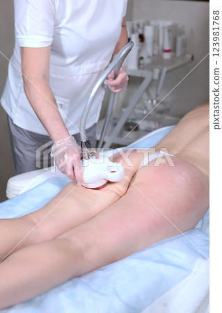 Figure correction in beauty salon. Ultrasound procedure for figure correction. Anti-cellulite and anti-fat Body care procedure. Vertical photo. 123981768