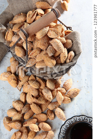 Salted almonds in a shell in a metal basket on white background. Top view. Natural protein and antioxidant. Vertical photo. Salted almonds in a shell in a metal basket on white background. Top view. Natural protein and antioxidant. Vertical photo. 123981777