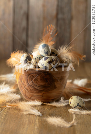 Quail eggs and feathers on a wooden table. 123981785