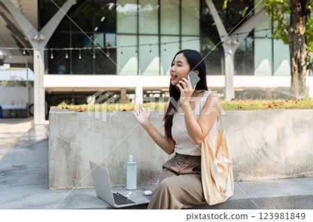 Sustainable communication. Young woman talking on the phone outdoors, promoting a sustainable lifestyle. 123981849