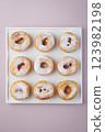 Donuts with powdered sugar on a light plate and a delicate purple background. Top view 123982198