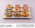 donuts with powdered sugar and various toppings on a white plate on a pale purple background. Top view . Copy space 123982200