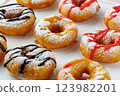 A group of donuts with powdered sugar and various toppings on a white plate close-up 123982201