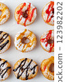 A group of donuts with powdered sugar and various toppings on a white plate close-up. Top view 123982202