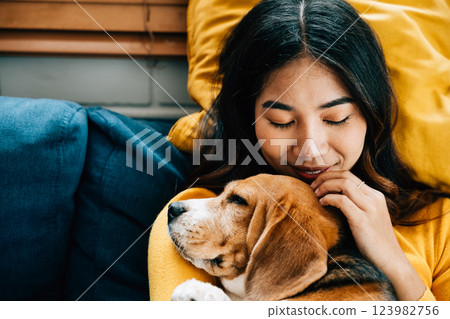 A portrait of happiness, a woman and her Beagle dog sleep peacefully on the sofa in the living room, embodying the concept of best friends forever and the joy of togetherness. Pet love A portrait of happiness, a woman and her Beagle dog sleep peacefully on the sofa in the living room, embodying the concept of best friends forever and the joy of togetherness. Pet love 123982756