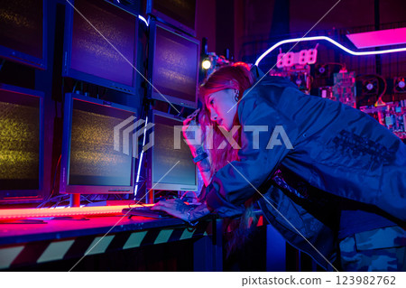 Asian woman wearing a black jacket hacking programming system and working with computer monitor display in dark office, Cyber security agency developing website cyber security, Monitoring Information 123982762