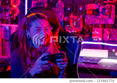 Gamer using joystick controller for virtual tournament plays online video game with computer neon lights dark room, woman wear gaming headphones playing live stream esports games console at home Gamer using joystick controller for virtual tournament plays online video game with computer neon lights dark room, woman wear gaming headphones playing live stream esports games console at home 123982778