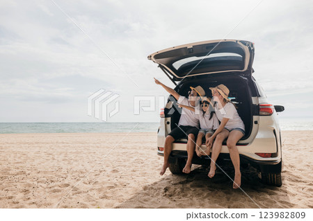 Happy Family Day. Family travel in holiday at sea beach, Dad, mom, daughter enjoy road trip sitting on back car and pointing finger out, people having fun in summer vacation on beach with automobile Happy Family Day. Family travel in holiday at sea beach, Dad, mom, daughter enjoy road trip sitting on back car and pointing finger out, people having fun in summer vacation on beach with automobile 123982809