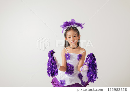 Smiling kid cheerleader in uniform with pom-poms. Studio portrait shows her youthful energy and love for cheerleading. cheerleader kid Smiling kid cheerleader in uniform with pom-poms. Studio portrait shows her youthful energy and love for cheerleading. cheerleader kid 123982858