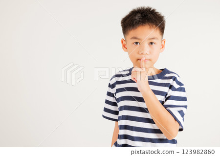 Young kid boy making finger on lips mouth silent quiet gesture, Happy Asian primary child marking silence for stop quiet, mute studio shot isolated on white background with copy space 123982860