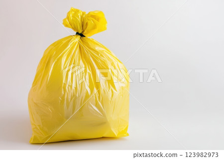 A bright yellow trash bag displayed prominently against a clean white background 123982973