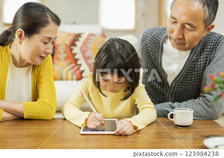 Grandparents watching their grandchildren studying on a tablet 123984238
