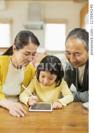 Grandparents watching their grandchildren studying on a tablet 123984240