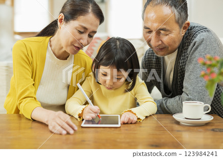 Grandparents watching their grandchildren studying on a tablet 123984241