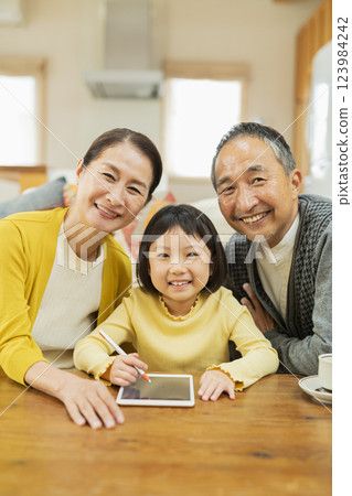 祖父母看著孫子在平板電腦上學習 祖父母看著孫子在平板電腦上學習 123984242