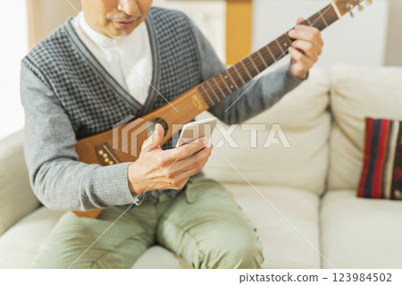 Senior man playing musical instrument at home Senior man playing musical instrument at home 123984502