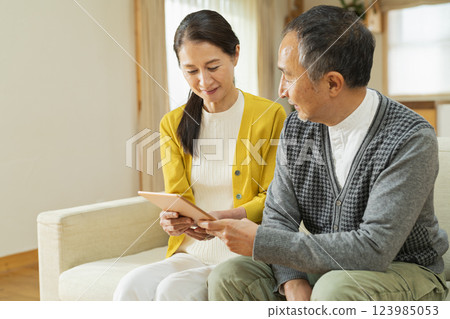 Elderly couple using a tablet device in the living room Elderly couple using a tablet device in the living room 123985053