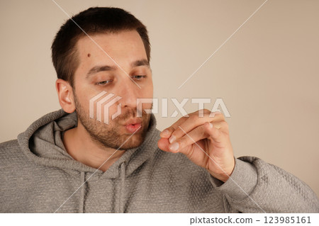 The bearded man is featured in a close-up, giving the impression he is blowing on his fingers. His natural look and casual pose create an engaging and relatable image. The bearded man is featured in a close-up, giving the impression he is blowing on his fingers. His natural look and casual pose create an engaging and relatable image. 123985161