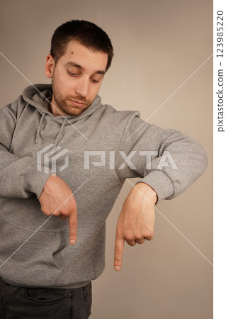 Pointing down with both hands, the man focuses attention on a lower point. His precise gesture is engaging and intentional. The image conveys clarity and purpose. 123985220