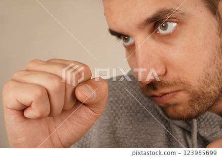 The image conveys a strong and focused attitude. A man in a sporty hoodie stands with clenched fists in a boxing stance. His posture suggests readiness and determination. 123985699